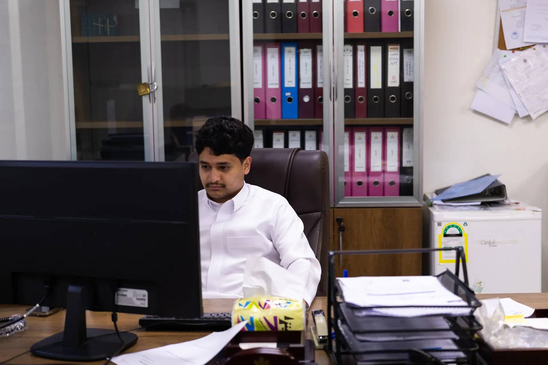 A team member in a white thobe working at a computer