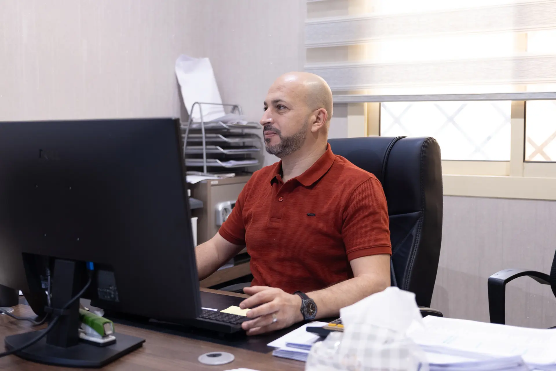 A team member in a red polo working at a desk