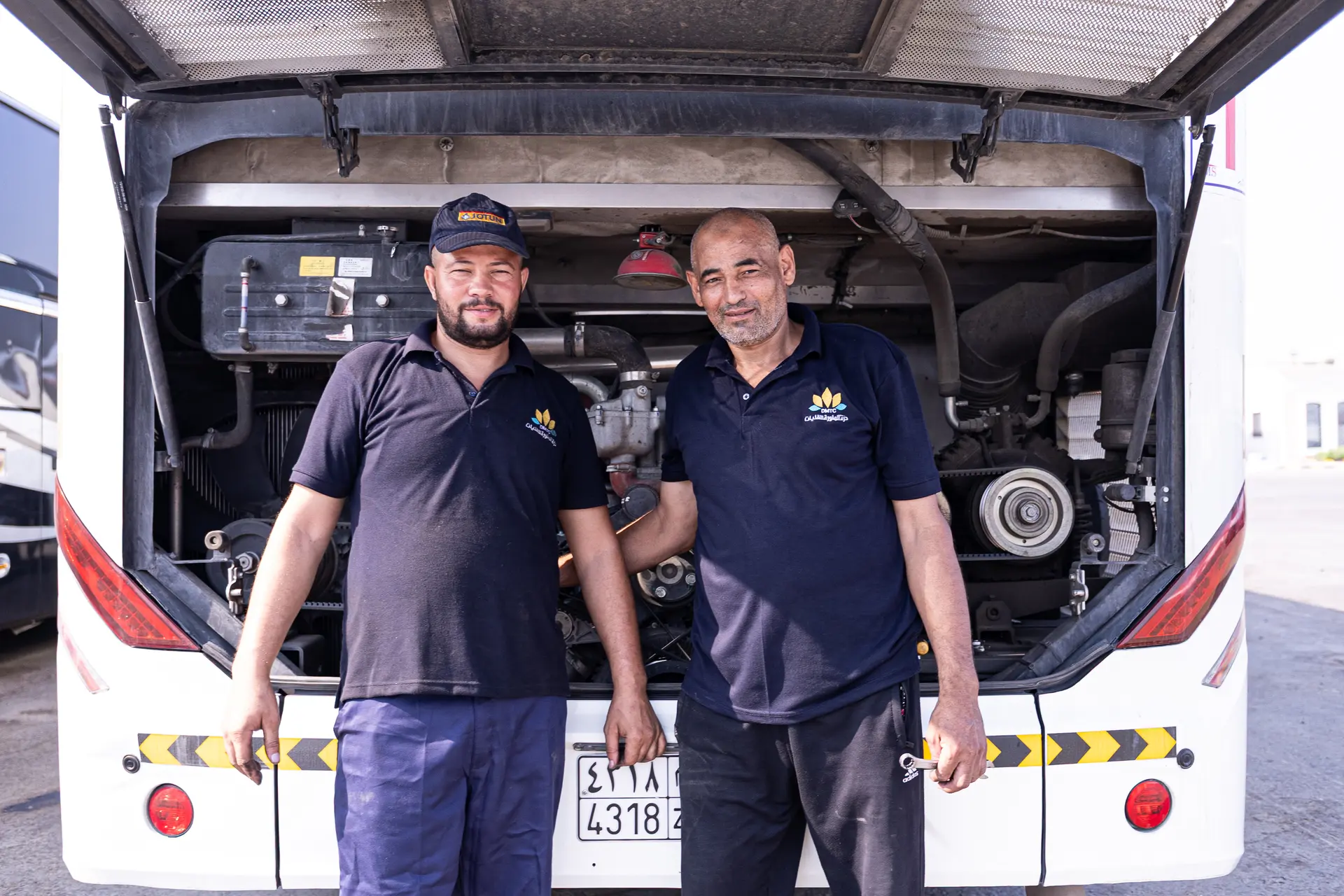 Two mechanics standing in front of a coach