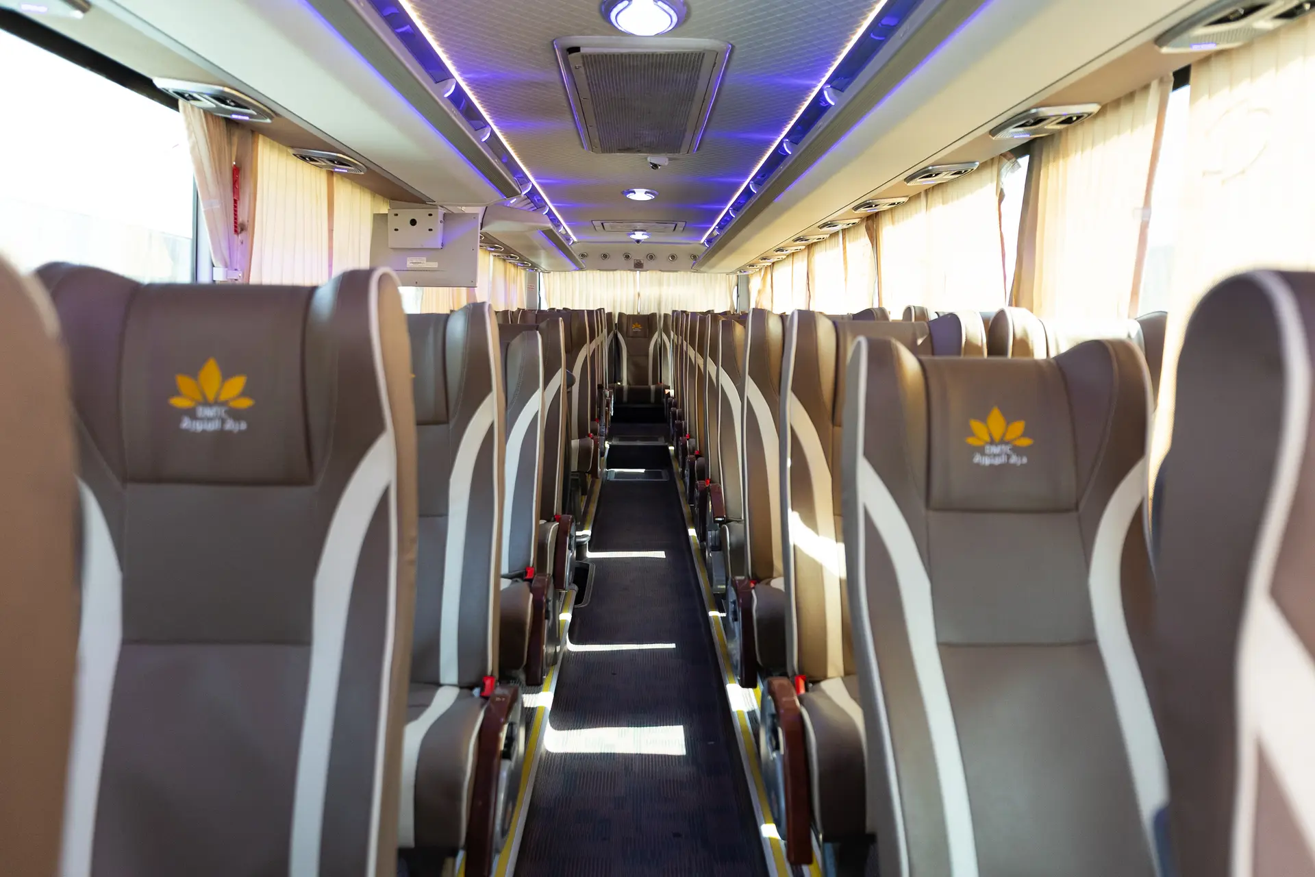 The aisle of a coach with beige and grey seats
