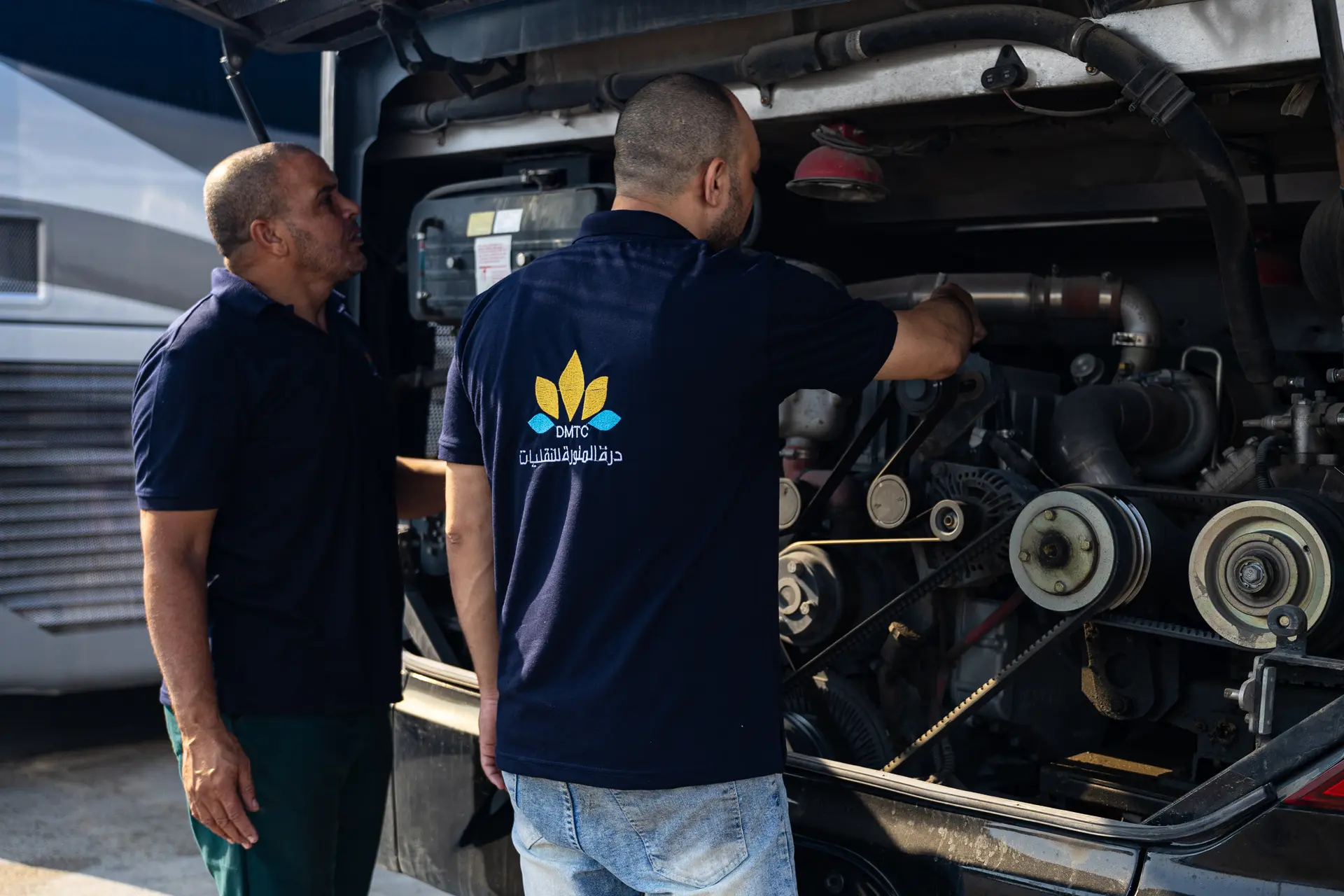 Two mechanics checking a coach engine from the rear