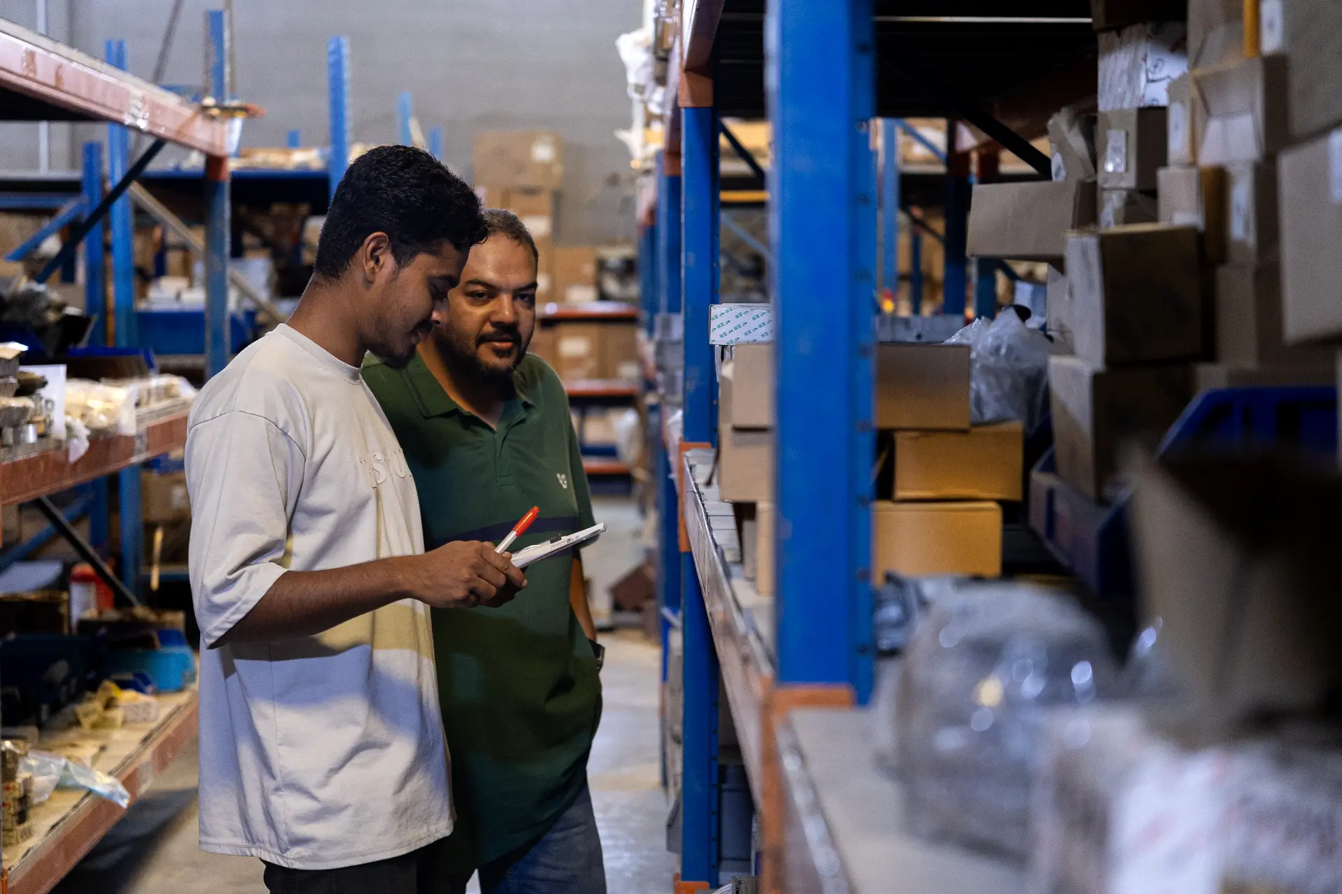 Two warehouse staff checking stock against a clipboard